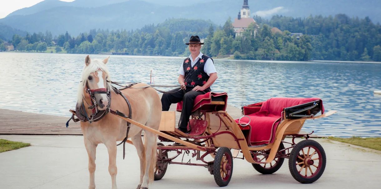 A coachman with his carriage by Lake Bled, the island church behind